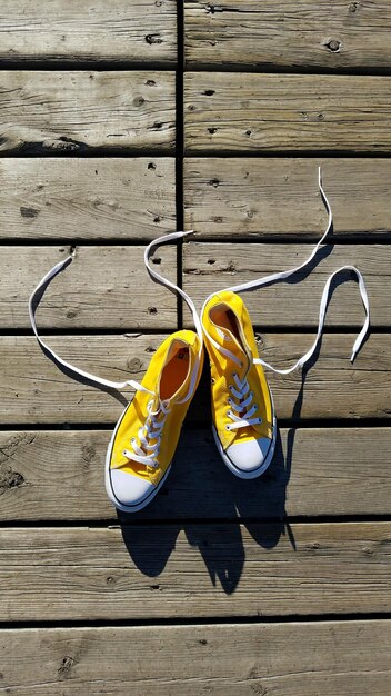 Foto directamente por encima de la toma de zapatos de lienzo amarillo en el suelo de madera