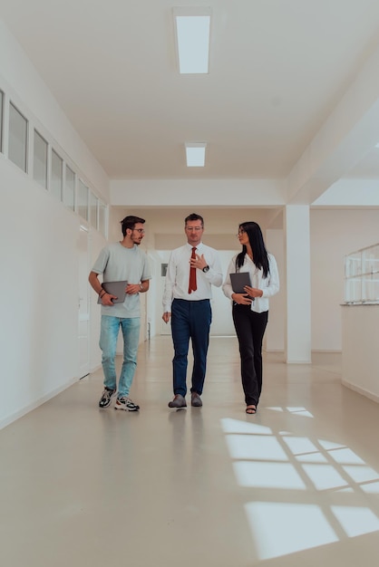 El director mantiene una conversación con la secretaria y un joven programador en un espacio moderno y espacioso.