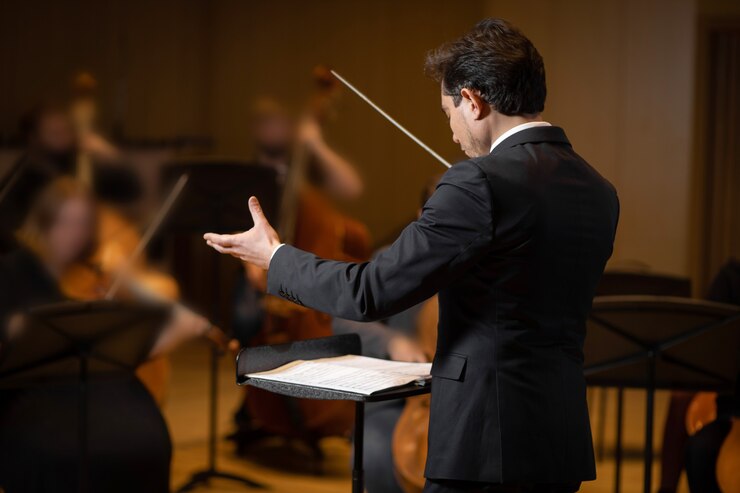 Foto director de orquesta sinfónica con artistas en el fondo de la sala de conciertos