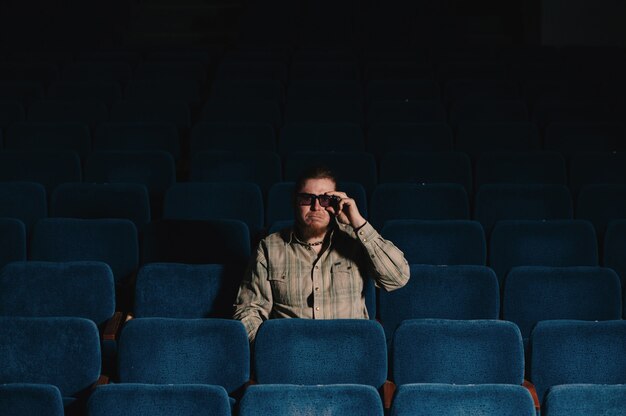 Director por uno en la sala de teatro oscuro. Retrato de hombre creativo en clave baja.