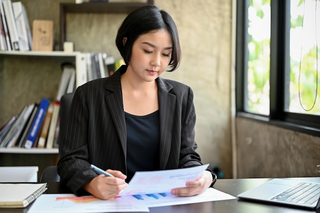 Una directora ejecutiva está revisando informes de marketing en su escritorio