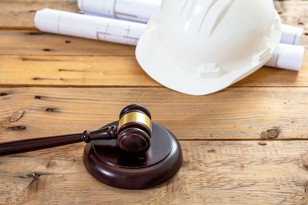 Direito do trabalho de construção martelo do juiz do capacete de segurança e planos de planta de construção na mesa