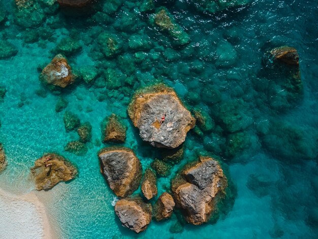 Direkt darüber frau im roten badeanzug am felsen umgeben vom meer griechenland urlaub