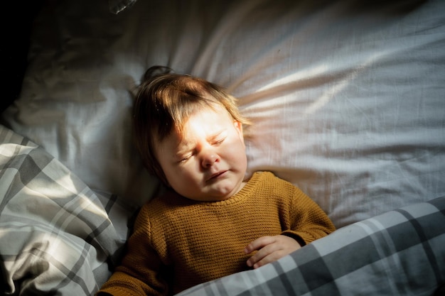 Direkt oben eine Aufnahme von einem süßen Jungen, der zu Hause im Bett liegt