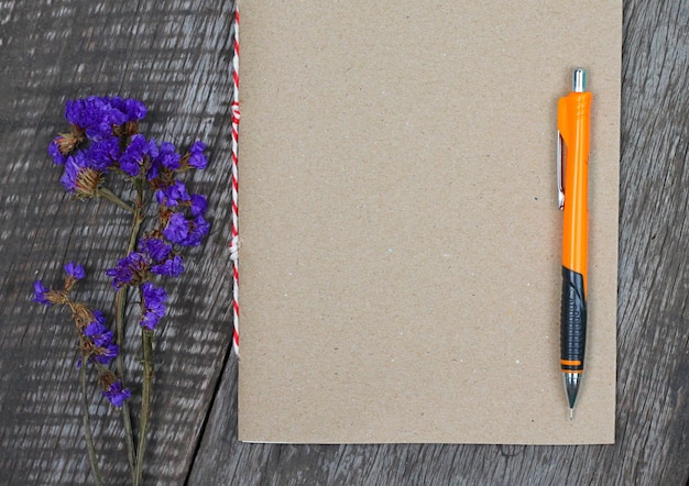 Direkt über Blick auf Blumen und Tagebuch mit Stift auf dem Tisch.