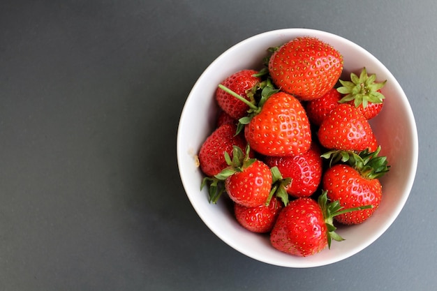 Direkt über dem Bild von Erdbeeren in einer Schüssel auf grauem Hintergrund