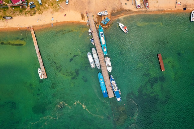 Direkt über dem Blick auf Boote und Yachten auf dem Pier auf einer unbewohnten Sandinsel am Baikalsee, Sibirien.