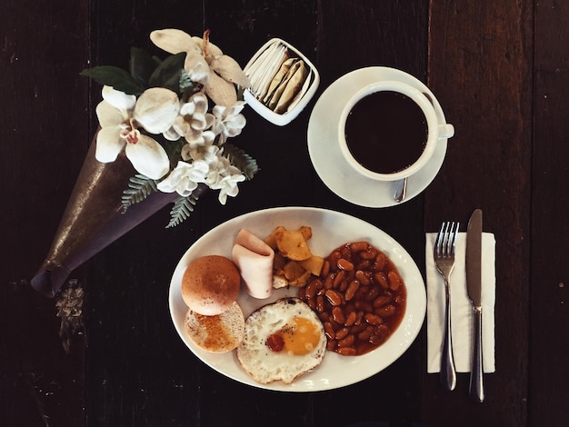 Direkt über dem Blick auf ein gesundes Frühstück mit schwarzem Kaffee und einem Blumenstrauß auf dem Tisch im Café