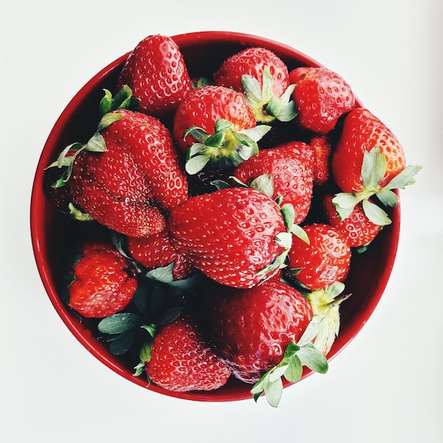 Direkt über dem Blick auf frische Erdbeeren in einer Schüssel auf weißem Hintergrund