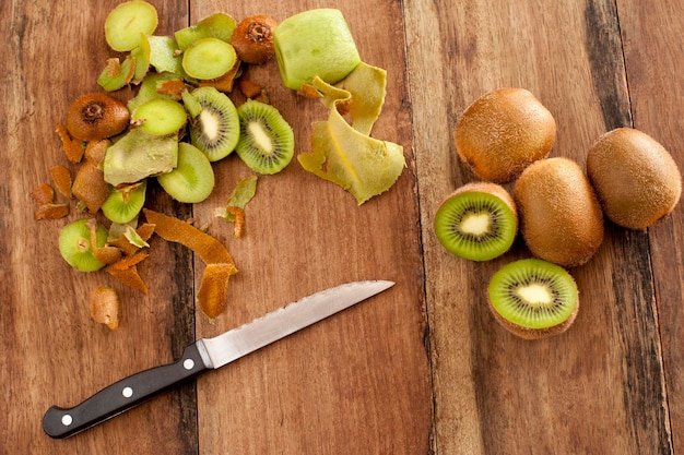 Direkt über dem Foto von Kiwis mit Küchenmesser auf einem Holztisch