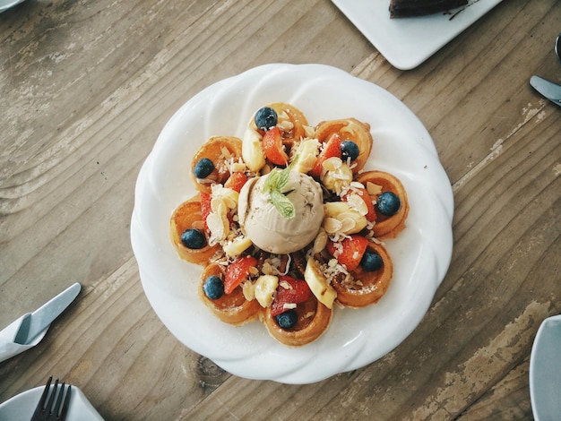 Direkt über dem Schuss Waffeln mit Obst und Eis auf dem Teller auf dem Tisch