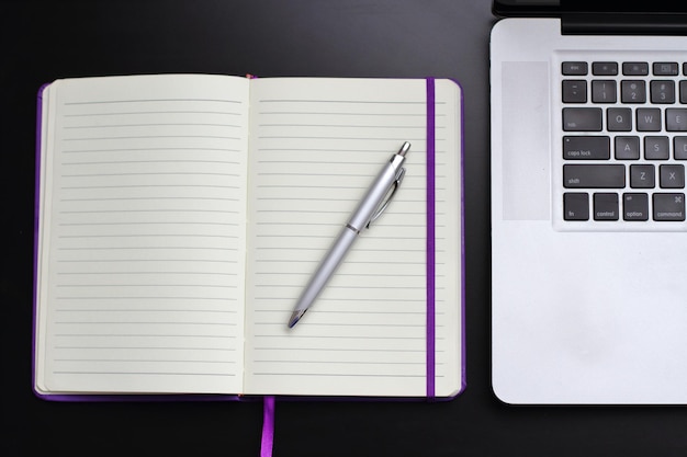 Foto direkt über dem tisch befindet sich ein offenes tagebuch und ein stift mit laptop