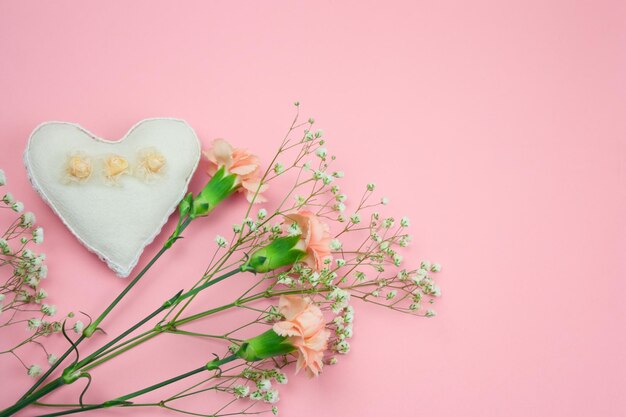 Direkt über der Herzform-Dekoration mit Blumen auf rosa Hintergrund