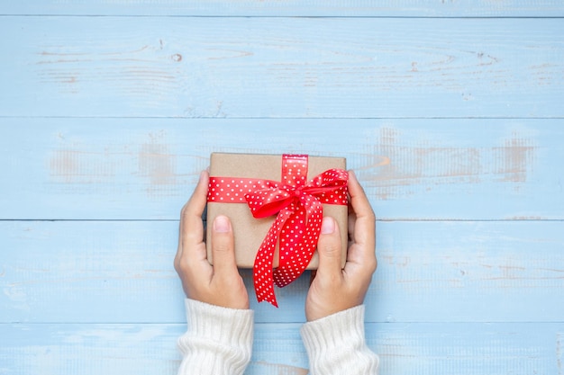 Foto direkt über der person, die eine geschenkkiste auf dem tisch hält