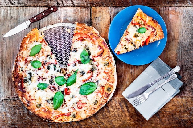 Diretamente acima da foto da pizza na mesa.