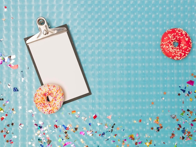 Foto diretamente acima da foto da prancheta com donuts e confetes coloridos na mesa