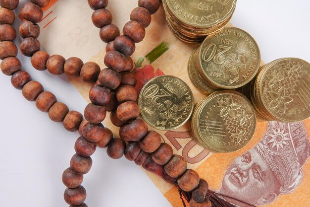 Foto diretamente acima da foto de contas de rosário com moeda da malásia em fundo cinza