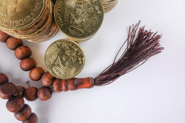 Foto diretamente acima da foto de contas de rosário com moedas empilhadas em fundo cinza