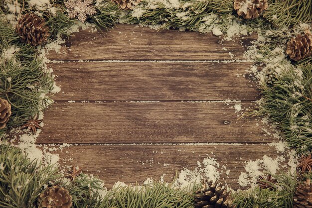 Diretamente acima da foto de plantas com neve e cones de pinheiro em mesa de madeira