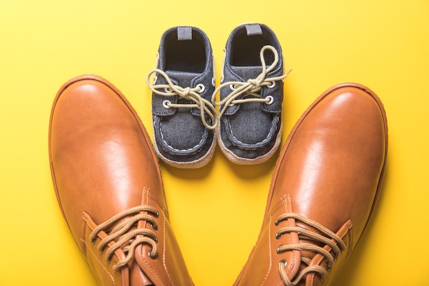 Foto diretamente acima da foto de sapatos e botas de bebê na mesa amarela