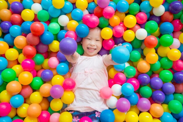 Foto diretamente acima da foto de uma menina brincando com bolas coloridas