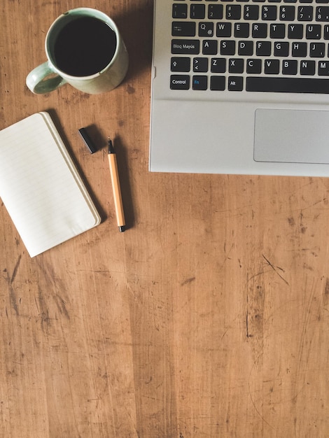 Diretamente acima da foto do laptop e da xícara de café na mesa de madeira