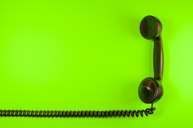 Diretamente acima da foto do receptor de telefone preto em fundo verde