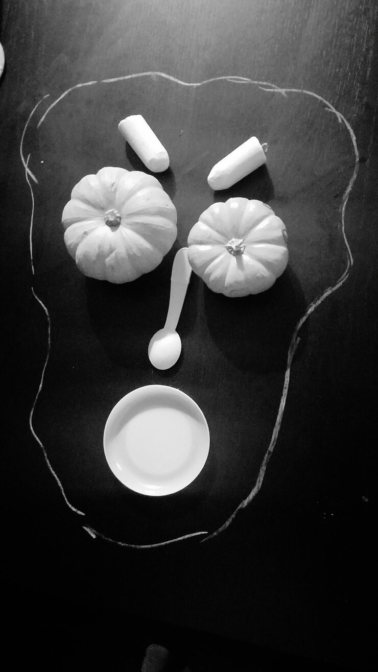 Foto diretamente acima da foto do rosto feita de abóboras e utensílios de cozinha na mesa
