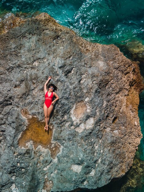Diretamente acima da mulher de maiô vermelho na rocha cercada pelas férias do mar na grécia