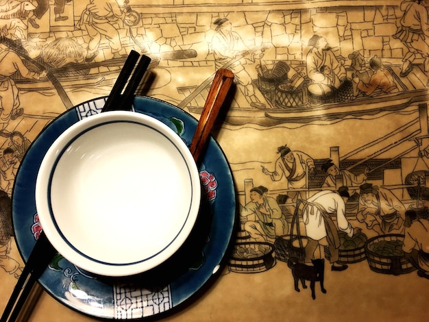Foto diretamente acima da taça de sopa e pauzinhos na mesa