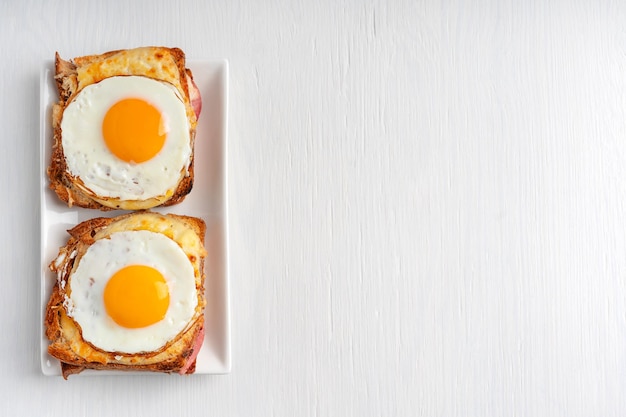 Diretamente acima da vista de sanduíches de Croque Madame fench quentes com queijo de presunto e ovo frito na mesa