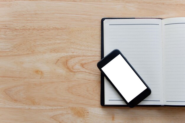 Diretamente acima da vista de um telefone inteligente com um livro na mesa