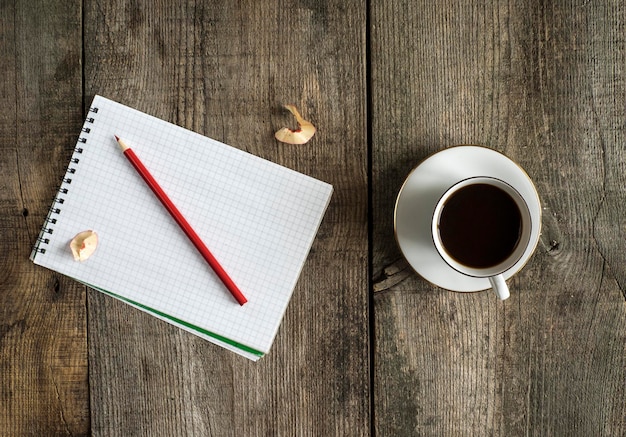 Diretamente acima da xícara de café e do bloco de notas com lápis na mesa
