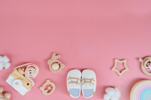 Diretamente acima de acessórios de bebê em fundo rosa Brinquedo de bebê de madeira bonito