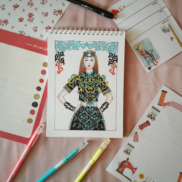 Foto diretamente acima de uma foto de canetas coloridas com um bloco de notas na mesa