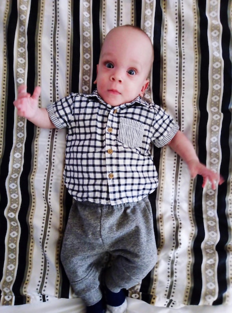 Foto diretamente acima do retrato de um menino bonito deitado na cama