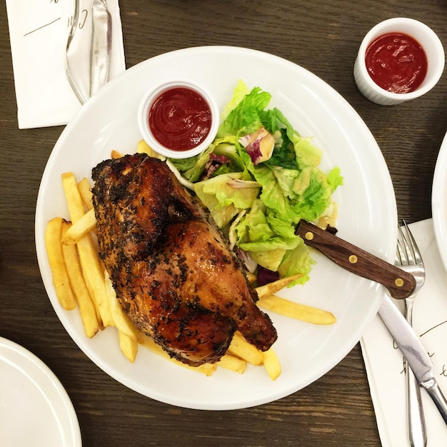 Foto diretamente acima do tiro de carne de frango com fogos franceses e salada no prato