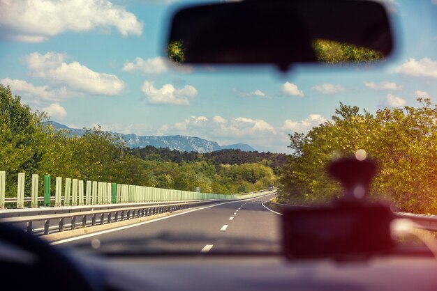 Foto dirigindo um carro na estrada em um dia ensolarado vista de um carro de uma paisagem montanhosa na primavera alpes itália europa