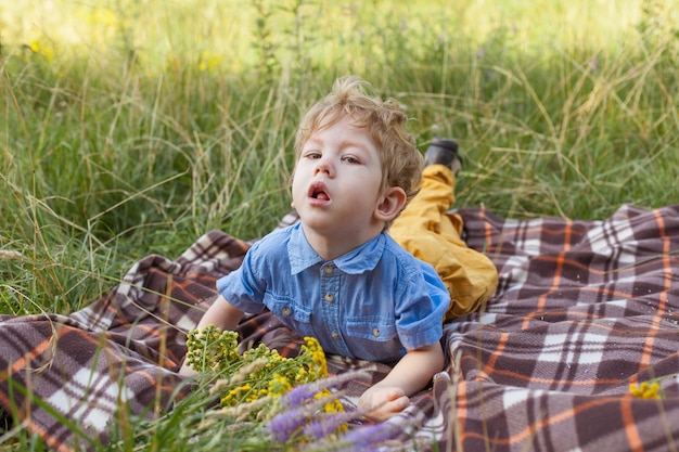 Discapacidad en un niño, niños con discapacidad, un niño acostado sobre una alfombra en el parque, parálisis en un niño.