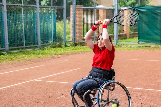 Discapacitados joven en silla de ruedas jugando tenis en la cancha de tenis.