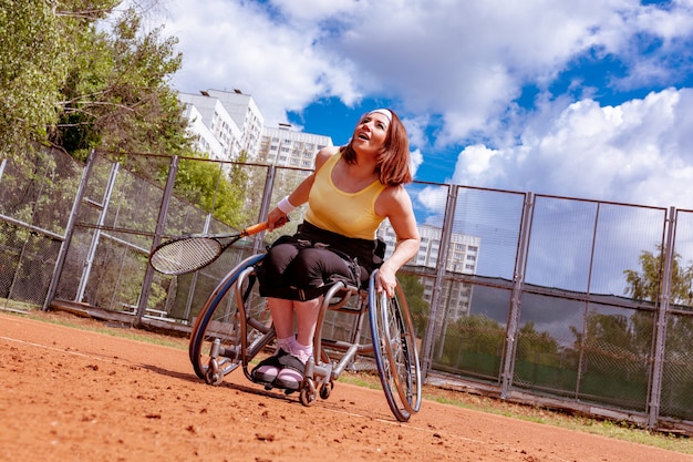 Foto discapacitados joven en silla de ruedas jugando tenis en la cancha de tenis.