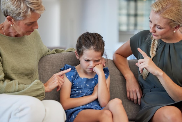 Disciplina familiar y advertencia por parte de la madre y la abuela, señal de mano a la niña por mal comportamiento en un sofá en casa Autismo adhd y comunicación por parte de padres e hijas en conflicto con problemas de actitud