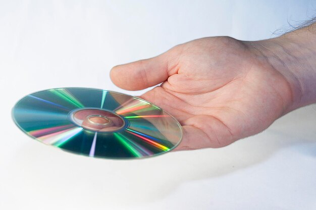 Foto disco de cd en mano masculina sobre un fondo blanco