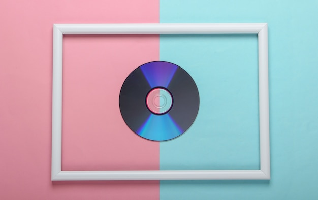 Disco CD en marco blanco sobre superficie pastel azul rosa