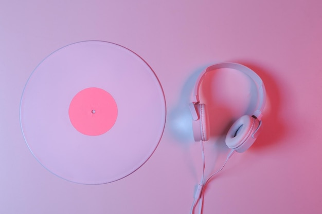 Disco de vinil branco com fones de ouvido em gradiente de luz de néon rosa azul Conceito de música minimalista Vista superior