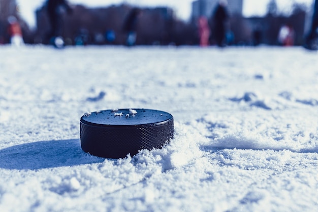 El disco de hockey se encuentra en el primer plano de la nieve