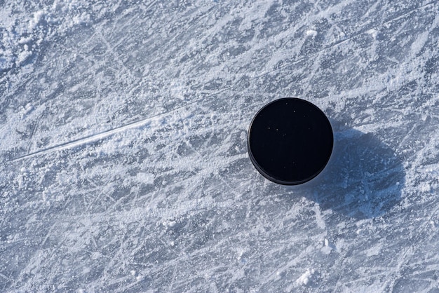 El disco de hockey se encuentra en el primer plano de la nieve