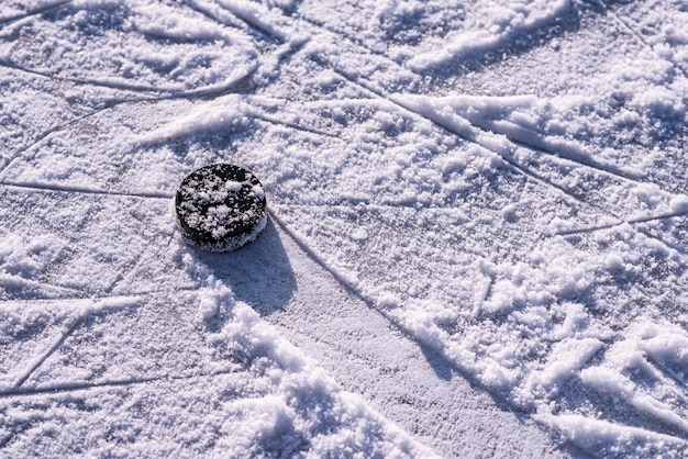 El disco de hockey se encuentra en el primer plano de la nieve