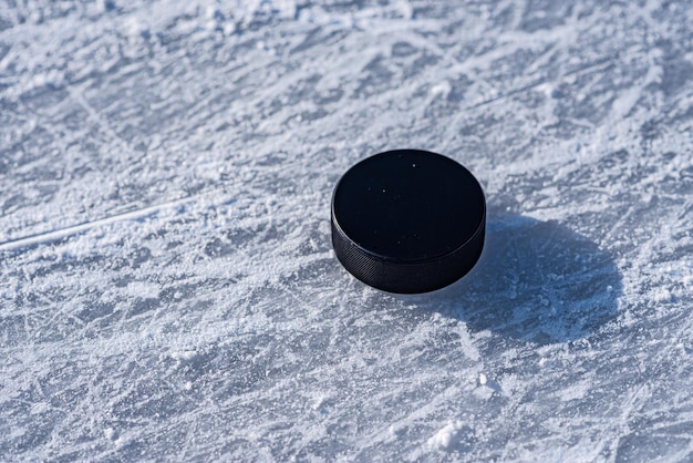 El disco de hockey se encuentra en el primer plano de la nieve
