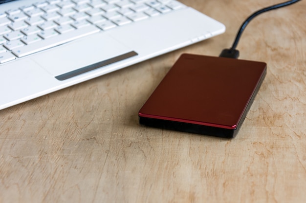 Disco rígido externo e teclado de laptop na mesa de madeira